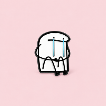 A seated white doodle character lets two long blue tears do the talking. A playful, relatable addition to a jacket, tote or backpack on a pale pink background.