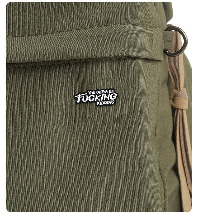 You Gotta Be Fucking Kidding Enamel Pin worn on an olive backpack