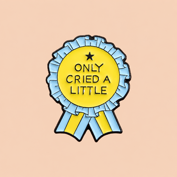 Yellow and light blue Only Cried a Little rosette enamel pin on a warm peach background
