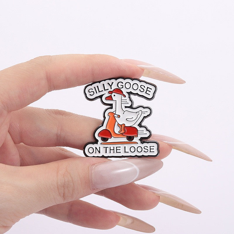Silly Goose on the Loose Scooter Enamel Pin held between fingers for scale